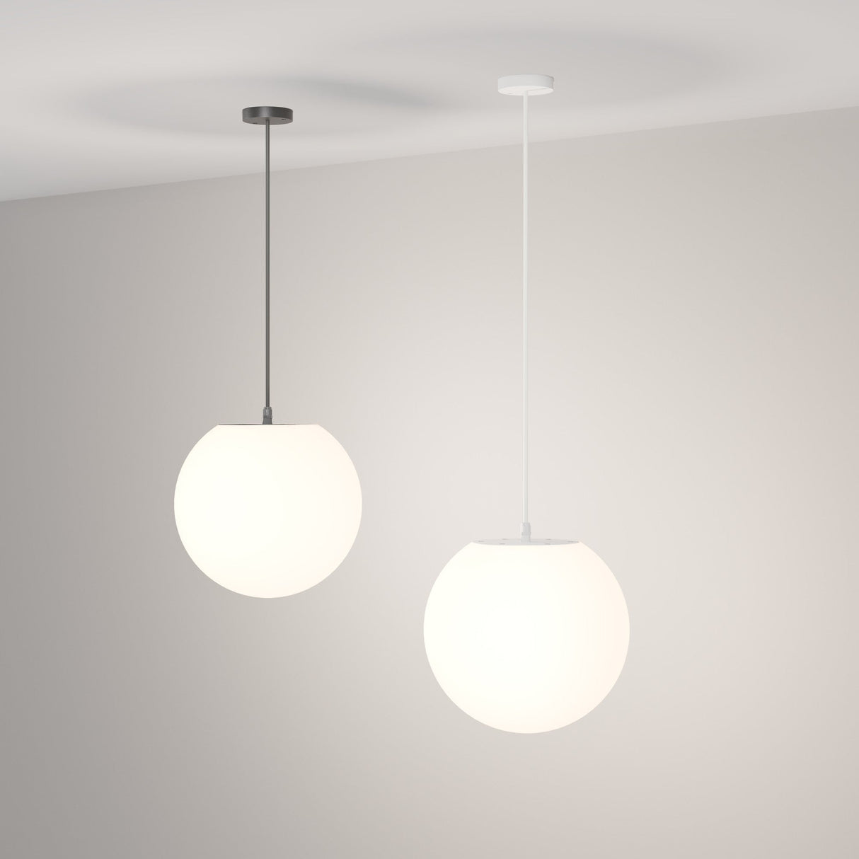 Two Erda Outdoor Pendant Lights, with spherical white shades and minimalist design, hang from the ceiling. The left light has a dark fixture while the right features a white fixture, both set against a plain white wall for a stylish and durable lighting solution.