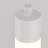 This close-up shows the Ray LED Long Pendant Light – White, featuring a minimalist cylindrical design. The top half is matte, while the bottom emits a soft glow. Its perfect for contemporary interiors and is suspended by a thin rod against a light gray background.