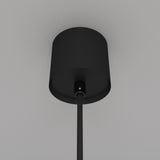 The Luna LED Globe Pendant Light 10cm 4000K in Black & White is a sleek, cylindrical, ceiling-mounted fixture that enhances modern interiors. It features a single downward rod, providing energy-efficient lighting against a light gray ceiling with an elegant design.