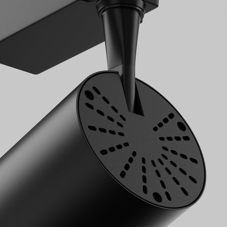 A close-up of the Vuoro S LED Single Phase Unity Track Spotlight 10W 3000K in black shows its sleek, cylindrical design with a perforated end and sleek connector. The minimalist spotlight, featuring an adjustable swivel for precision, is set against a plain gray background.