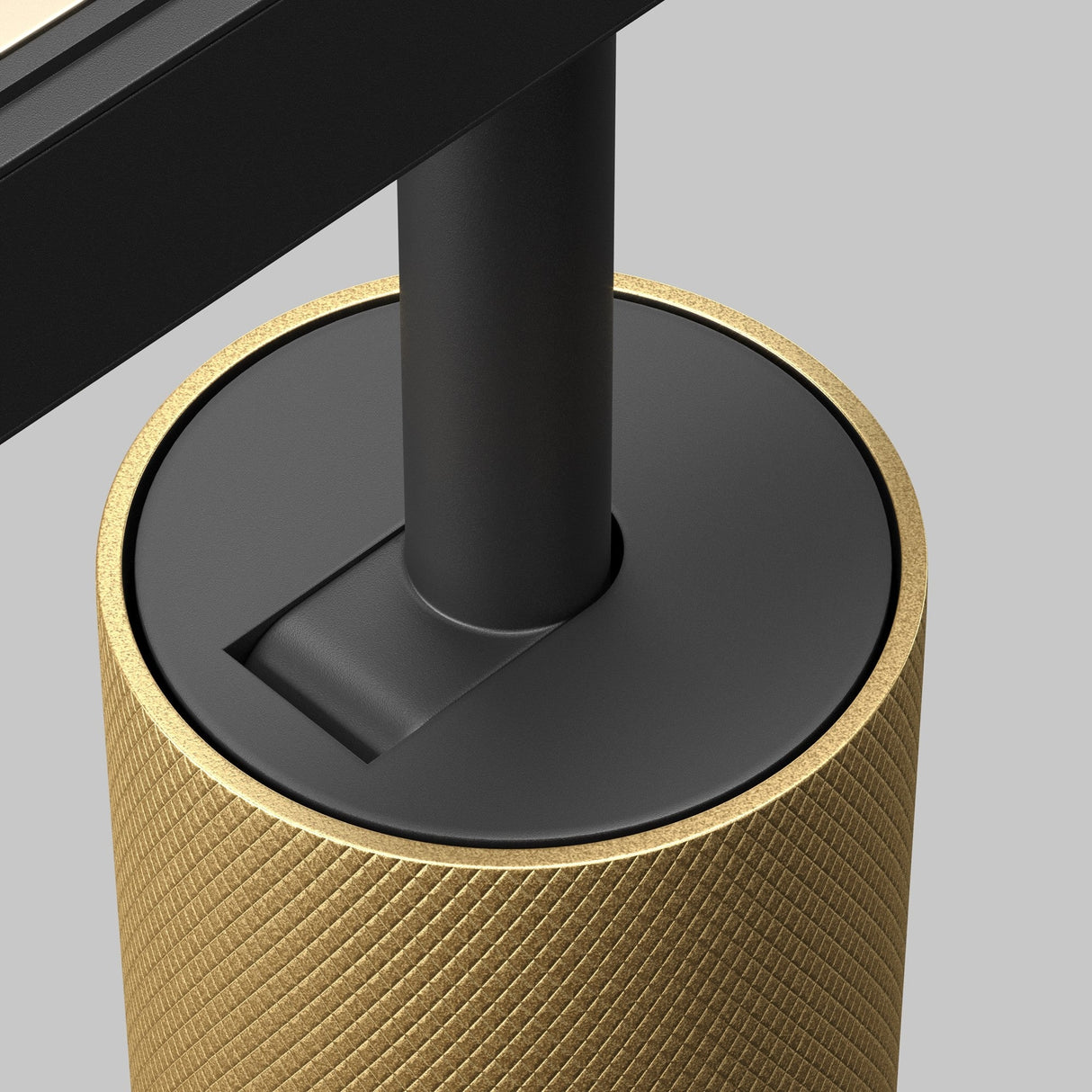 A close-up highlights the Artisan LED Magnetic Exility Track Spotlight 12W 4000K, featuring energy-efficient lighting. It has a black cylindrical post on a quilted matte gold base, against a neutral gray background that enhances its modern, minimalist appeal.
