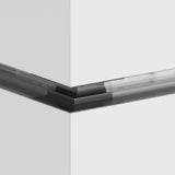 The S35 Tracks Recessed L-Shape External Corner Connector in black is a sleek, modern architectural detail, accentuating the intersection of two white panels. A transparent component enhances the minimalistic design.