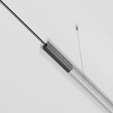 The Exility Track Power Feed - Black (TRA034B-42B) is a minimalist linear pendant light fixture, suspended by two thin cables against a white background. With its sleek design and modern aesthetic, it features a black power strip.