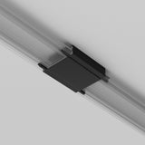 A black rectangular object, likely a Radity Magnetic Track Straight Power Connector - Black, is attached to the ceiling within a linear metallic track. It contrasts against the white ceiling, implying a modern magnetic track lighting or support system.