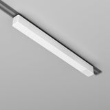 A sleek Radity Track Power Supply 100W in white, with a modern rectangular design and subtle vent-like pattern, is mounted on the light gray ceiling. This magnetic track light fixture is discreetly powered by a 48V supply.