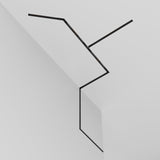 The Exility Magnetic Recessed Track 1m for Plasterboard 12.5mm in black is seamlessly integrated into the white ceiling and wall, creating a zigzag pattern with minimalist elegance.