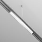The Exility Recessed Track Power Supply 100W - White features a minimalist, sleek rectangular design. Suspended with a thin, black cable from the gray ceiling, it offers energy-efficient lighting with a bright glow to enhance modern aesthetics.