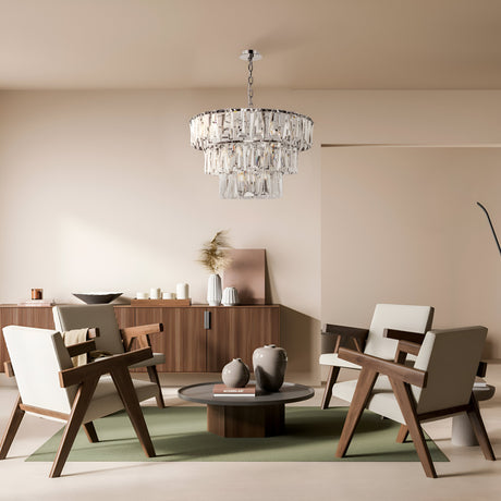 A modern living room showcases four wooden chairs around a circular coffee table. Above, the Puntes 18 Light Chandelier in chrome adds elegance. The room includes a sideboard with decor on a light floor and a green oval rug, all set against neutral walls.