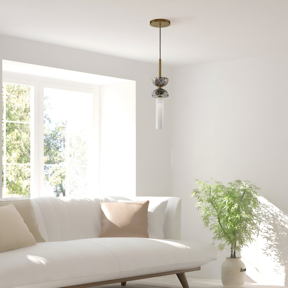 A minimalist living room exudes modern elegance with a white sofa and beige cushions by a large window. The Kyoto Pendant Light - Gold & Grey Marble Base gracefully hangs from above, while a potted green plant on its grey marble base adds a touch of nature to the serene setting.