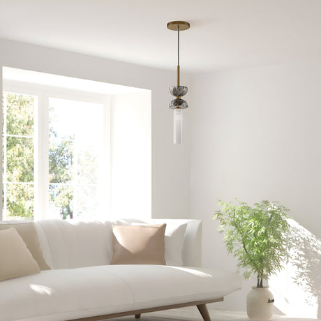A minimalist living room exudes modern elegance with a white sofa and beige cushions by a large window. The Kyoto Pendant Light - Gold & Grey Marble Base gracefully hangs from above, while a potted green plant on its grey marble base adds a touch of nature to the serene setting.