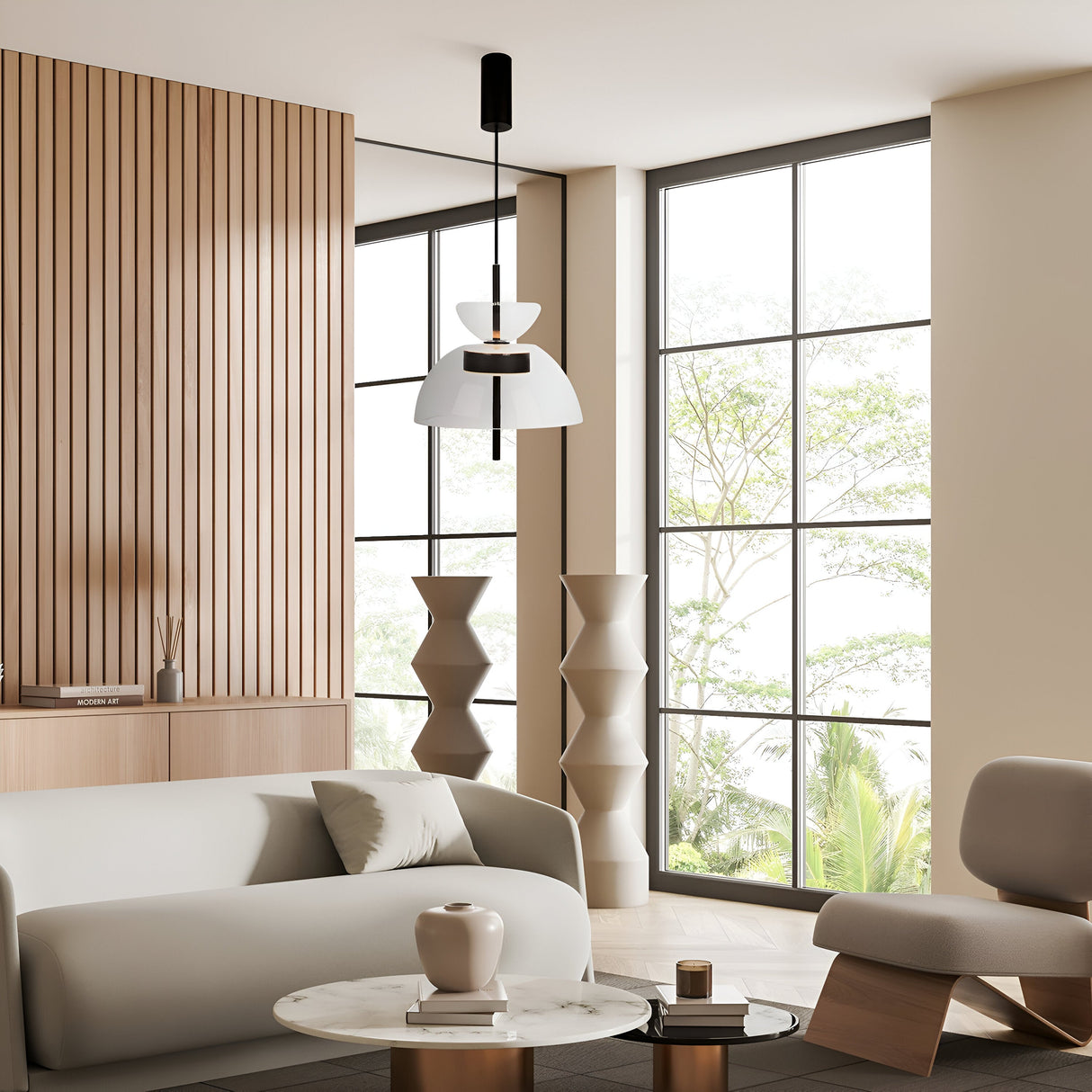 A modern living room with contemporary interiors features minimalist design, a light gray sofa, round marble coffee table, and sleek armchair. Large windows illuminate geometric sculptures and wooden wall paneling, while the Bangkok LED Pendant Light 25cm - Black With Clear Glass Shade hangs above.