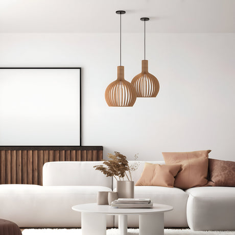 Minimalist living room with a white sofa, beige pillows, and round coffee table. Two Black Roots Pendant Lights with beige wooden globe dome shades accent the ceiling. A blank picture frame, wooden panel on the wall, and vase with dried plants enhance this natural beige-toned space.