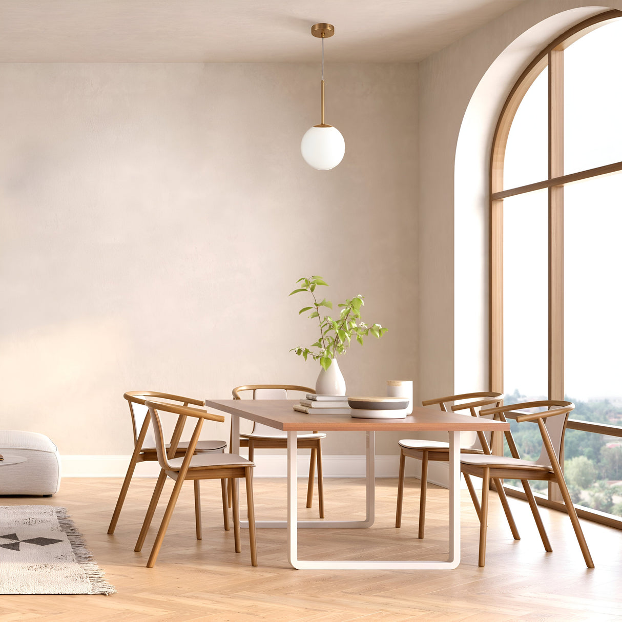 A modern dining room features a wooden table with six matching chairs. A white vase with green branches and two cups adorn the table, beneath the striking Basic Form Globe Pendant Light 18cm in gold with frosted white glass. An arched window, light wood floor, and neutral walls complete the serene space.