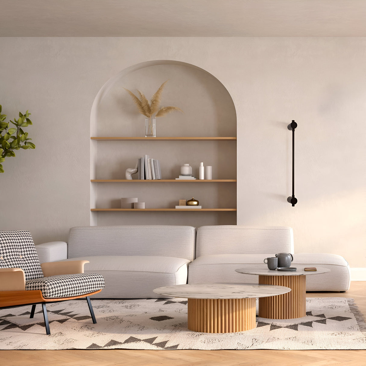 A modern living room showcases a white sectional sofa with a houndstooth armchair. Two wooden round coffee tables complement a geometric rug and sit in front of built-in shelves, decorated in an arched alcove and illuminated by the Rotta LED Wall Light 6W 3000K - Black. A plant adds greenery.