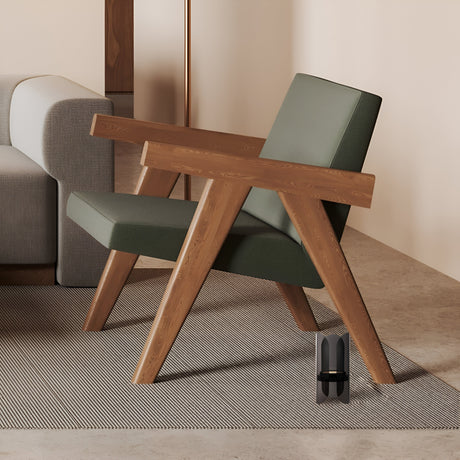 In a modern living room, a wooden armchair with green cushions stands next to a gray sofa under ambient light. The setup rests on a textured gray rug atop a stone floor, complemented by an Insight LED Table Lamp - Black and a small black sculpture near the armchair.