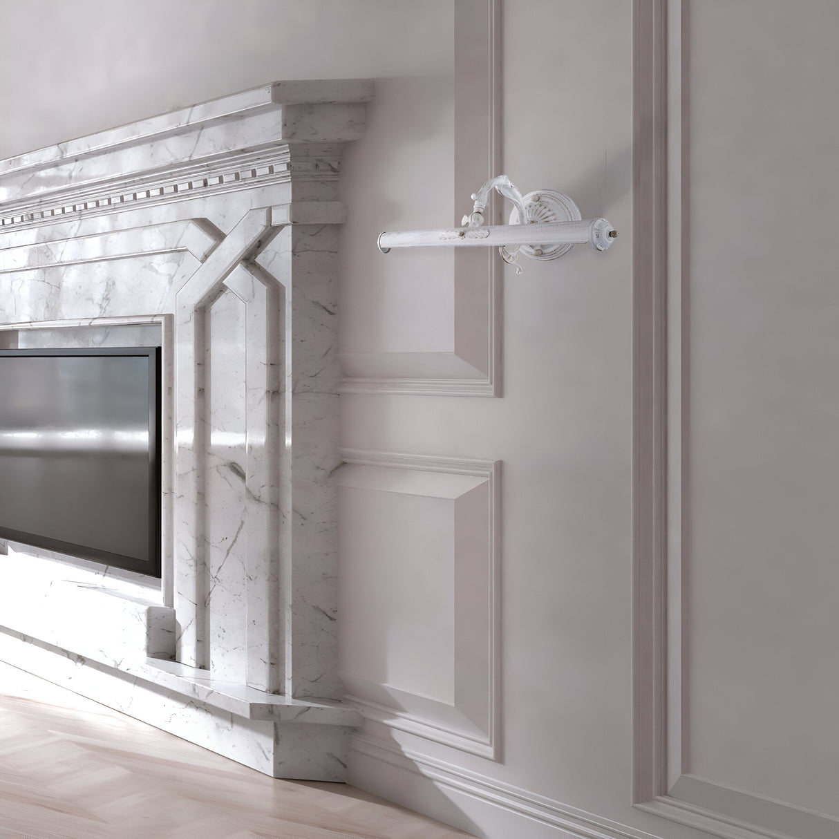 The room features an elegant marble fireplace with intricate detailing and a built-in flat-screen TV. A Picasso Classic Picture Light - White adds vintage charm, enhancing the luxurious design. A decorative wall sconce adorns the light gray paneled wall, and the polished wooden floor completes the look.