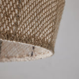 Close-up of the Jahari Woven Jute Pendant Light in natural, showing the coarse open-knit jute weave and raw rim edge against a plain light grey background.