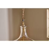 Kalsi Large Recycled Glass Pendant Light in Lustre, close-up of the flagon-shaped shade with smoky gold shoulder, brass collar, chain, and visible lampholder stem against a neutral wall.