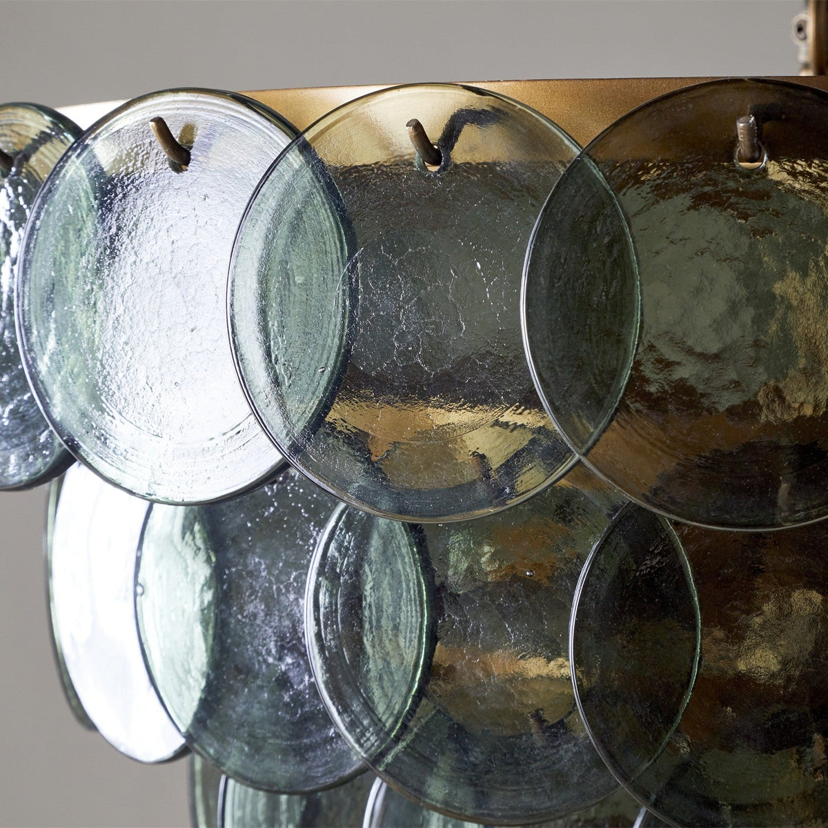Close-up of the Kagitha Large 3 Light Recycled Glass Chandelier, showing overlapping round green glass discs hooked onto a brass ring frame.
