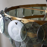 Close-up of the Kagitha Large 3 Light Recycled Glass Chandelier, showing overlapping green glass discs hooked onto a brass ring frame.
