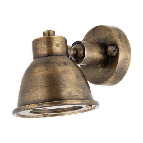 Kasai Brass Wall Spotlight in antique brass, with a round wall plate, knuckle joint, and adjustable domed bell-shaped head, shown against a plain white background.