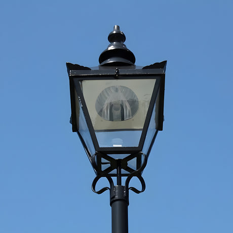 Large Victorian replacement lantern head in black metal with a pointed finial and glass panels, shown against a plain blue sky, for 77mm post fitting.