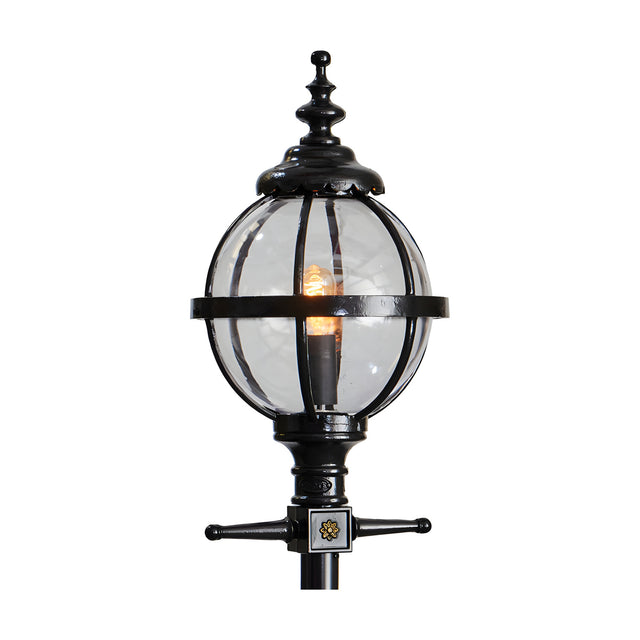 Cast iron globe lantern head in black with clear glass panels and ornate finial top, shown lit on a plain white background, designed to fit a 62mm spigot post.