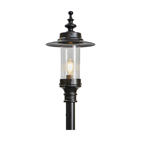 Cast iron Georgian lantern head in black with clear glass cylinder, exposed bulb, and decorative finial cap, shown mounted on a black post against a plain white background.