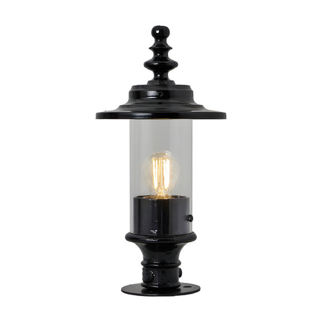 Cast iron Georgian lantern head in black with clear glass cylinder, ornate finial top and 44mm spigot fitting, shown lit on a black pedestal base against a plain white background.