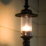 Cast Iron Replacement Georgian Lantern head in black with cylindrical clear glass shade and ornate finial, illuminated against a wall, 44mm fitting.