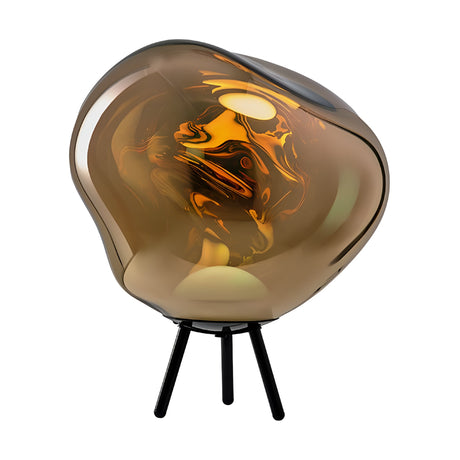 The Lava Large LED Floor Light - Gold features an irregular, organic-shaped gold glass shade atop three slender black legs, providing warm, glowing light and creating abstract reflections for a striking modern look.