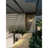 Ruka Floor Lamp in anthracite, slim bollard-style outdoor lighting lining a wooden pathway to a modern entrance with warm glow at dusk.
