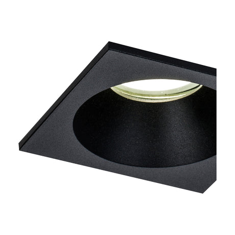 Close-up of the Comfort IP54 square downlight in matt black aluminium, showing the deep recessed reflector and GU10 lamp housing against a white background.