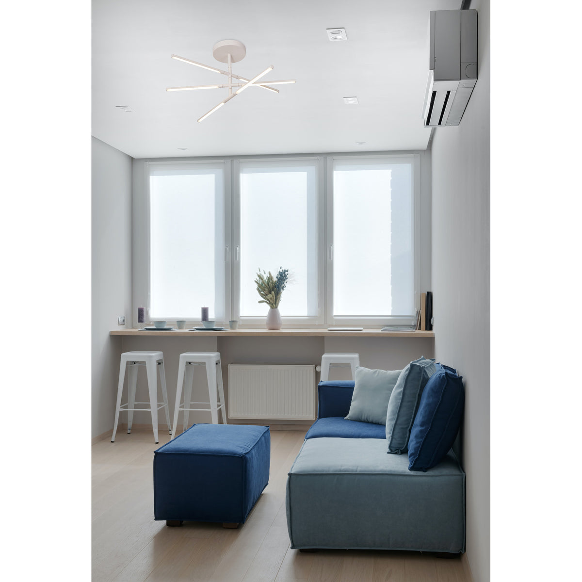 Torch Semi Flush Ceiling Light 73cm in sand white, with five slim LED bars arranged in a crossed pattern, mounted on a white ceiling above a living room seating area.