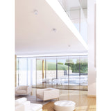 Gower Spotlight 7W 3000K 80mm in sand white, shown recessed into a white ceiling above an open-plan living space with glass doors and neutral furnishings.