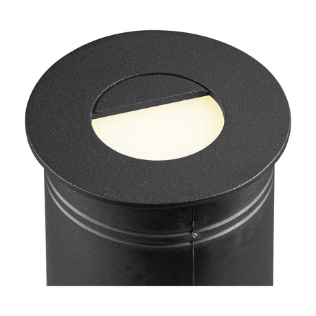 Aspen IP65 Eyelid Recessed Outdoor Wall Light in sand black, close-up of the round cylindrical fitting with hooded eyelid aperture casting warm white LED light, shown on a white background.