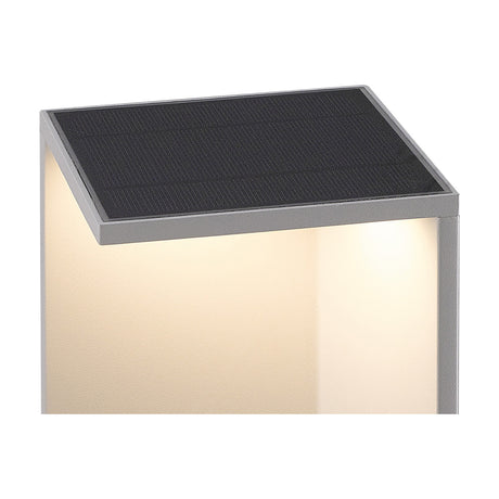 Close-up of the Chevalier IP54 bollard light's square graphite top with integrated solar-style panel, showing warm LED glow along the aluminium body against a white background.