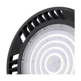 Close-up of the Urano IP65 UFO downlight in black, 26cm aluminium body with vented rim and integrated LED rings behind a clear lens, 150W 5000K daylight, on a white background.