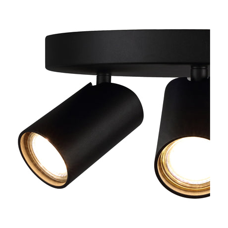 Close-up of the Sal 3 Light GU10 Round Spotlight in matt black, showing two adjustable cylindrical heads with GU10 bulbs lit, mounted on a round ceiling plate against a white background.