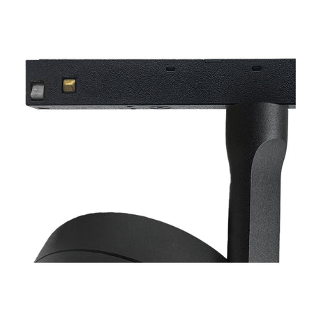 Close-up of the Magneto Disc track light in black, showing the compact disc-shaped head with connector pins mounted on the track adaptor arm against a plain white background.