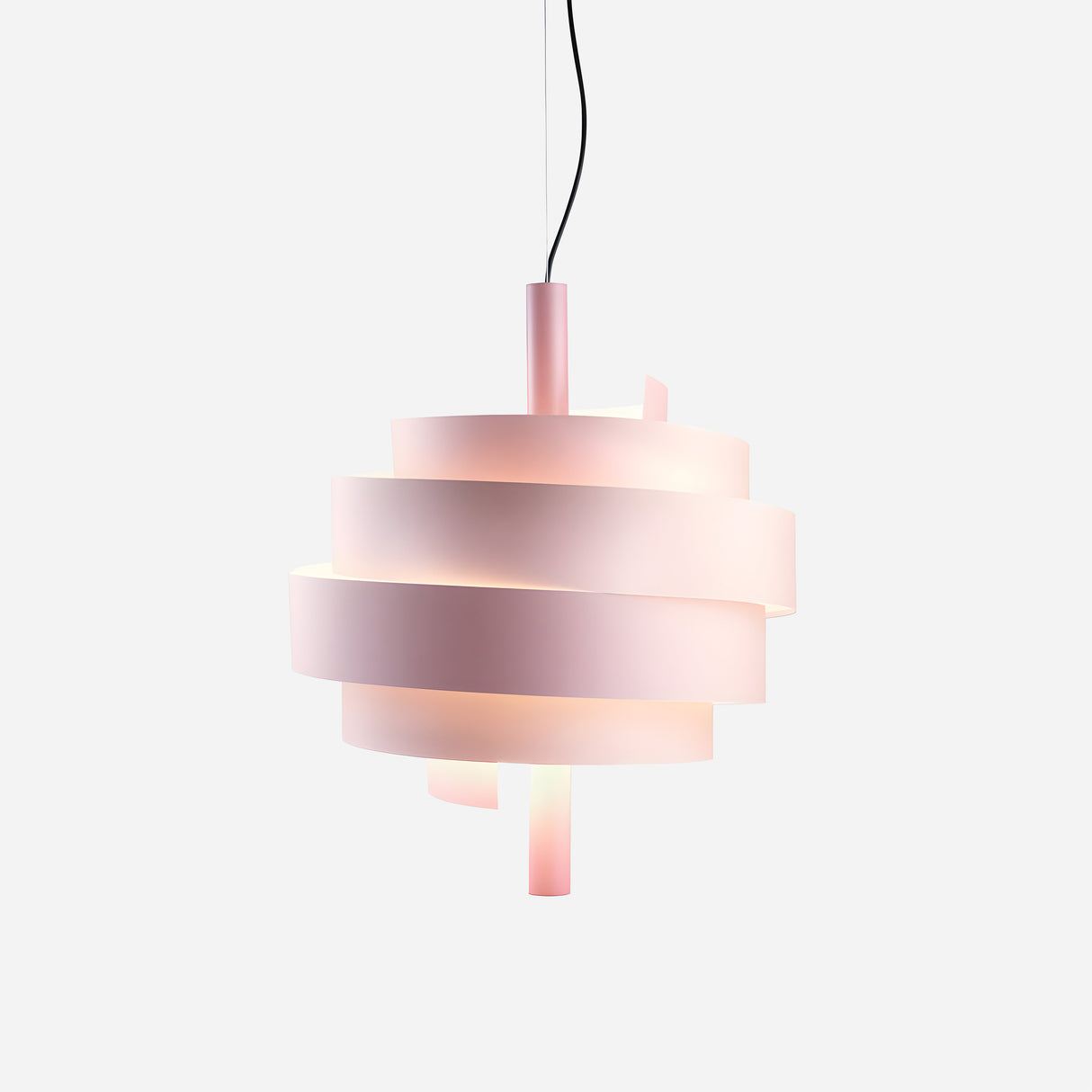 The Picasso Pendant Light - Pink showcases a spiralling ribbon design consisting of layered, translucent bands with a pink finish. Suspended from a sleek black cord against a plain white backdrop, this modern light is softly illuminated to highlight its contemporary and artistic style.