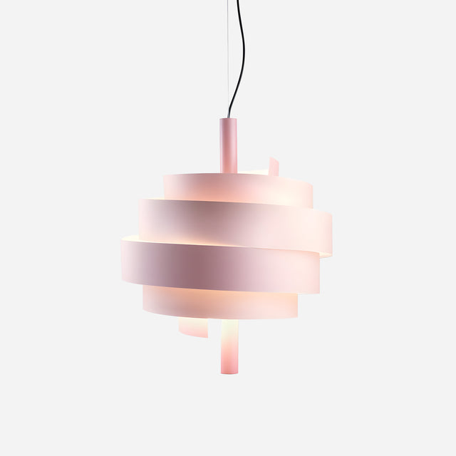 The Picasso Pendant Light - Pink showcases a spiralling ribbon design consisting of layered, translucent bands with a pink finish. Suspended from a sleek black cord against a plain white backdrop, this modern light is softly illuminated to highlight its contemporary and artistic style.