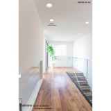 Cabrera Downlight, 132mm cut-out, 12W 3000K matt white, recessed into a hallway ceiling above a wooden staircase with glass balustrade.