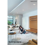 Formentera recessed downlights with matt white bezels installed in a living room ceiling, illuminating a neutral interior with sofa, rug and wood-panelled wall.