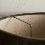Close-up of the Mendai Medium Lampshade in moss green velvet, showing the pale linen interior lining and metal lamp frame support.