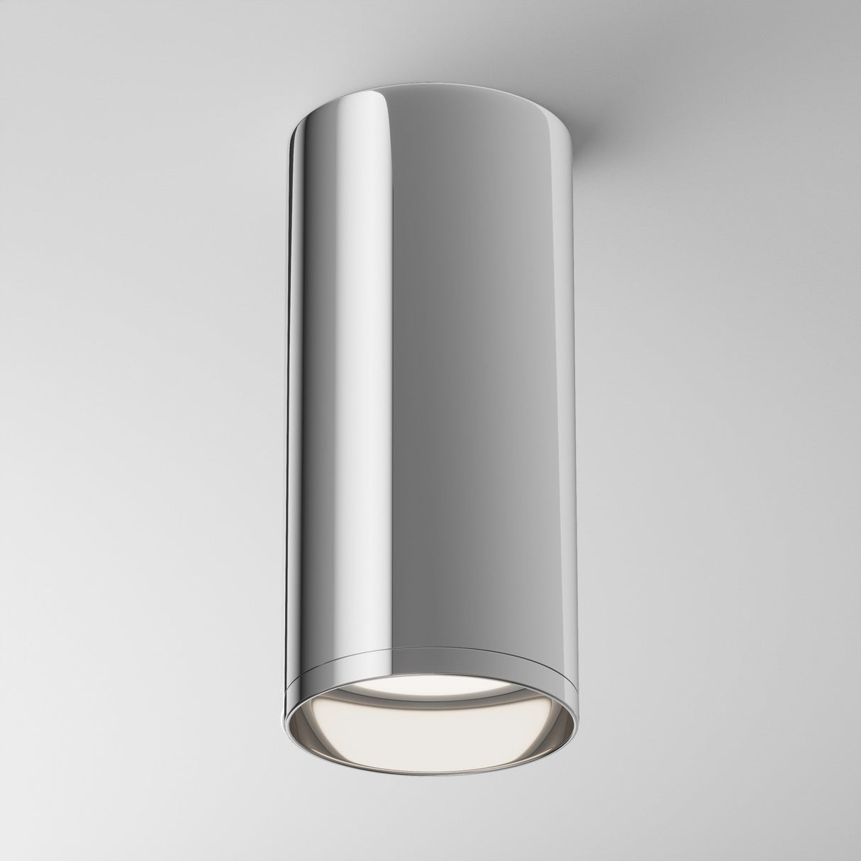 The Focus Fixed Round Surface Mounted Downlight in chrome features a polished, cylindrical design. Perfect for modern settings, it emits bright white light downward, enhancing any white ceiling background.