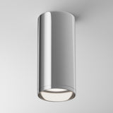 The Focus Fixed Round Surface Mounted Downlight in chrome features a polished, cylindrical design. Perfect for modern settings, it emits bright white light downward, enhancing any white ceiling background.