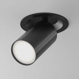 The Focus S Single Recessed Spotlight in black is a chic cylindrical fixture mounted on a white ceiling, directing light gracefully downwards. Perfect for minimalist interiors, it boasts a sleek and modern aesthetic with its refined black finish.