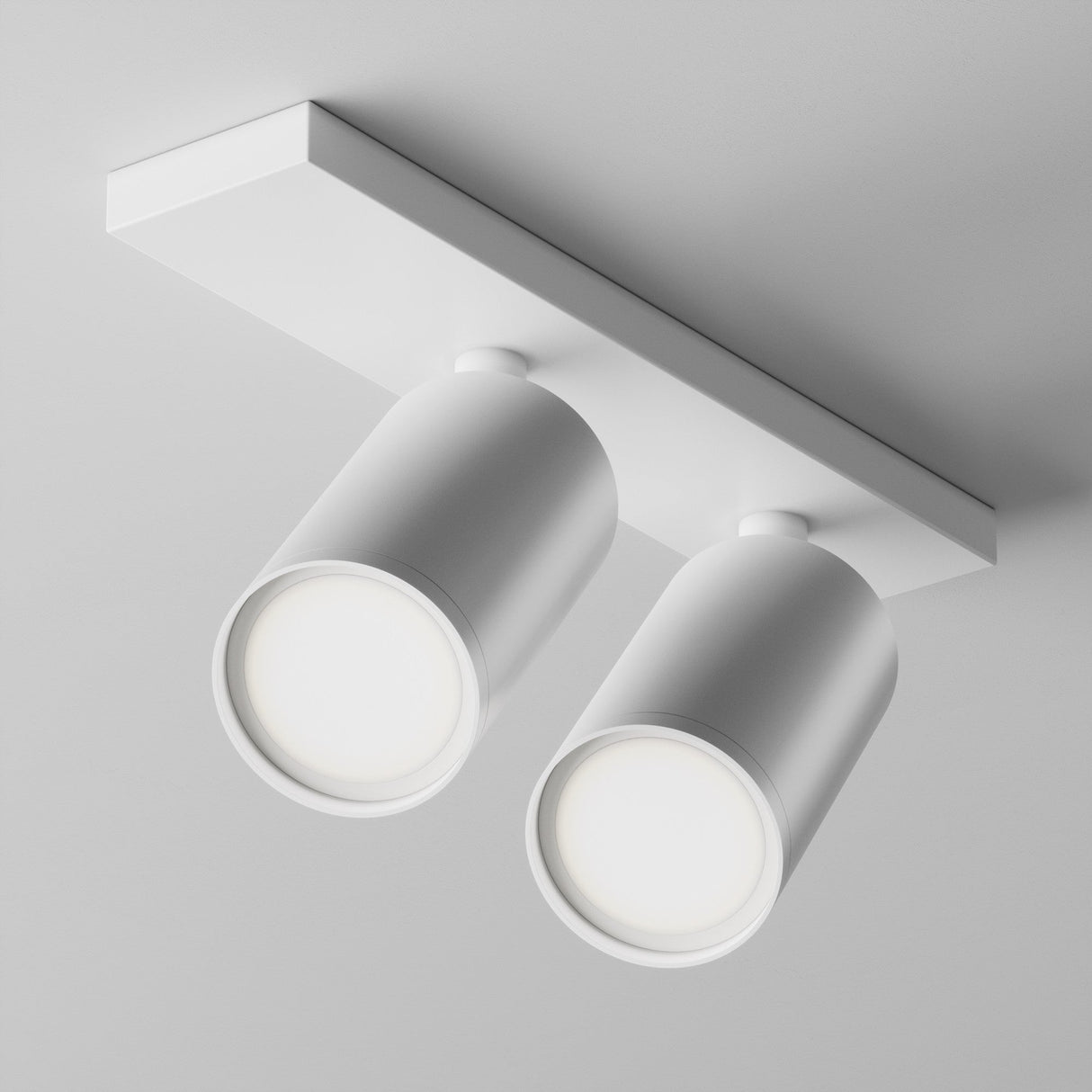 The Focus S Twin Bar Spotlight - White is a modern, minimalist fixture with two adjustable cylindrical white lights on a rectangular base, emitting a soft glow that blends seamlessly with the ceiling.