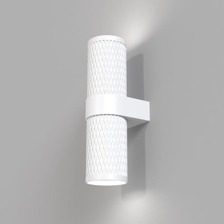 The Focus Design Up & Down Wall Light - White, featuring a modern cylindrical shape with a textured, lattice-like surface, is mounted on a gray wall. It emits soft up and down lighting in a white glow from both ends for subtle illumination.